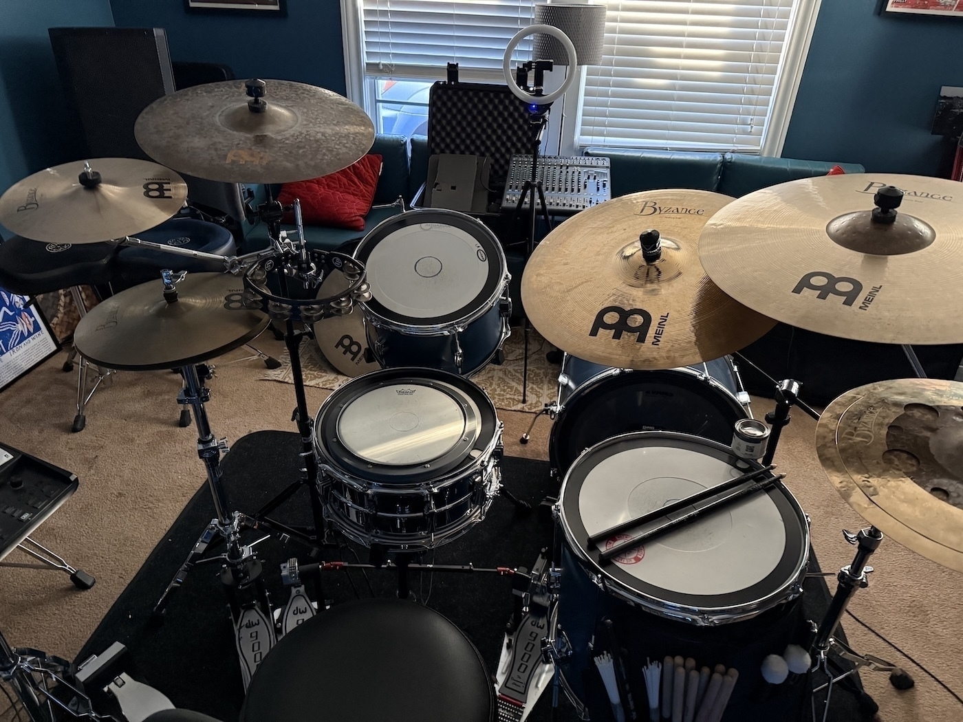 Auto-generated description: A drum kit is set up in a room with various cymbals and drum pads, surrounded by music equipment.